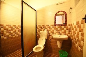 A small bathroom with a toilet, sink, and a mirror with a decorative frame. - Ideal Ayurvedic Resort (Neyyattinkara)