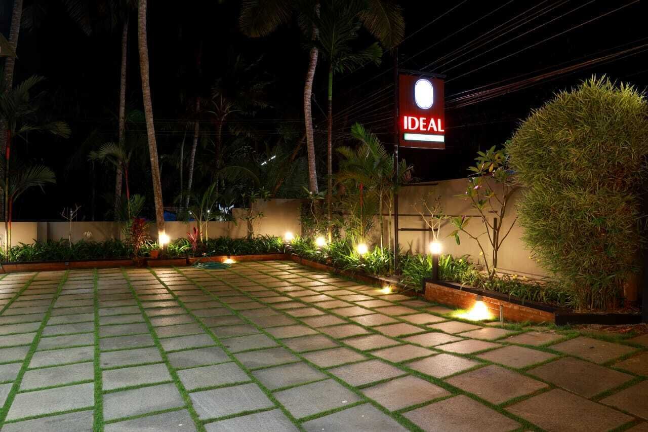 A well-lit outdoor area with a paved walkway, surrounded by lush greenery and palm trees.
