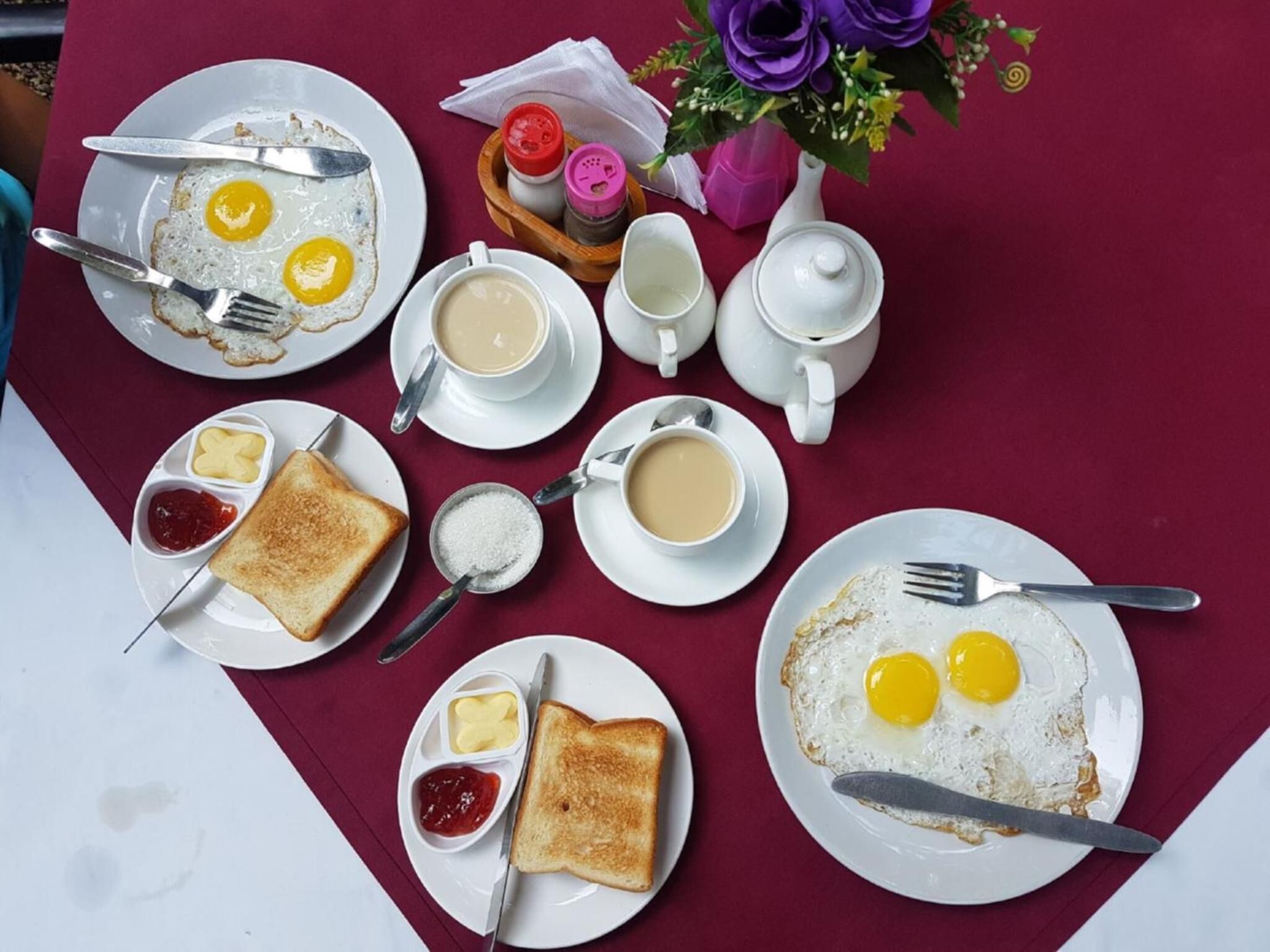 A breakfast setting with eggs, toast, coffee, and tea on a table.
