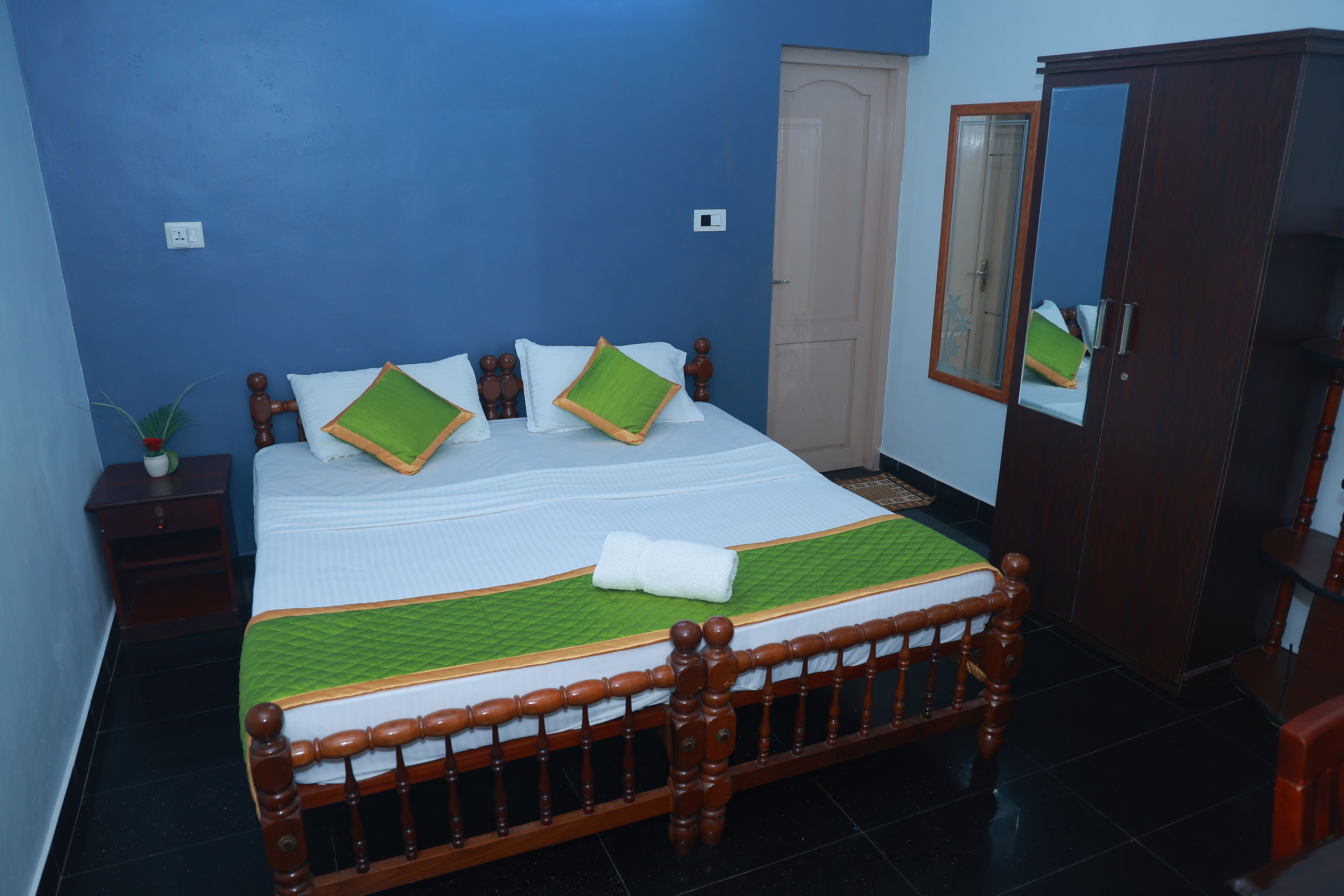 A neatly made bed with a green quilt, wooden headboard, and white bedding.