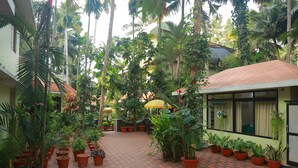 Un patio con plantas en macetas, piso de tejas rojas y un edificio con un letrero que dice "Consultation Room 2".
