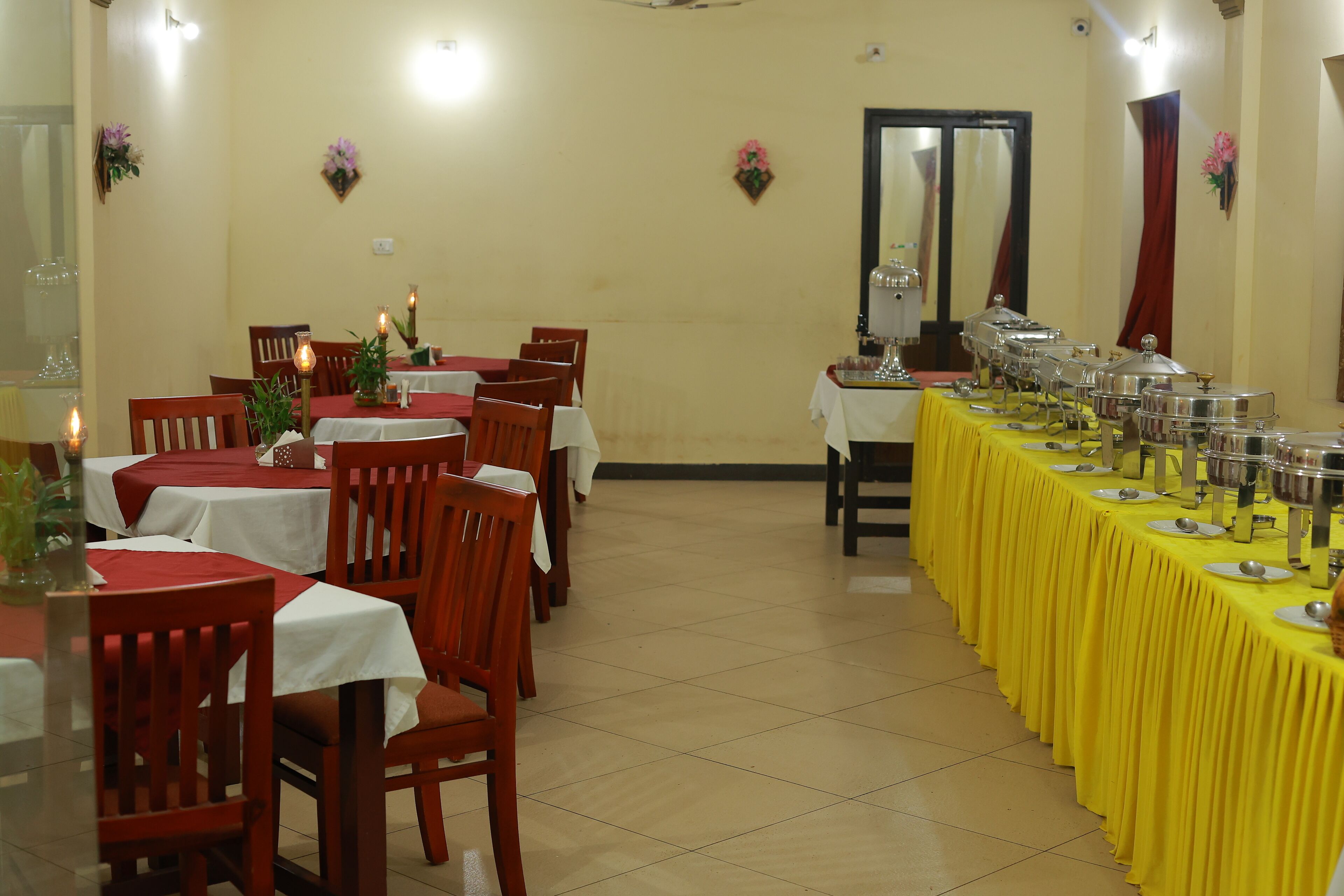 Un espace repas avec des tables dressées pour les repas, des chaises et un buffet où sont disposés des récipients contenant les plats.