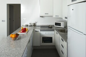 Una cocina moderna con encimera de granito, electrodomésticos de acero inoxidable y un cuenco de fruta.