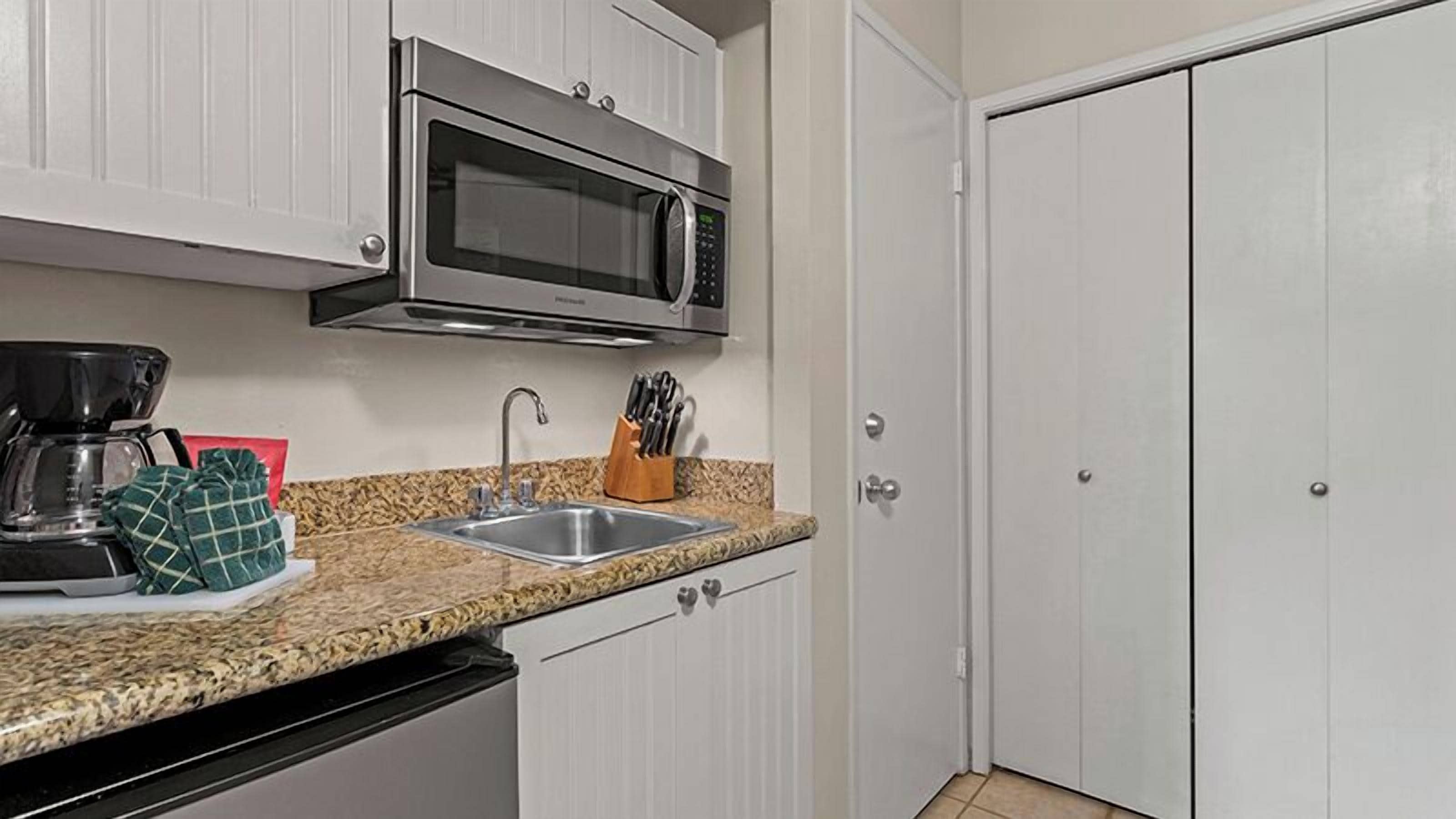 A kitchen with a microwave, sink, and cabinet doors.