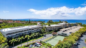 Ett modernt hotell med flera byggnader, en parkeringsplats och en tennisbana.