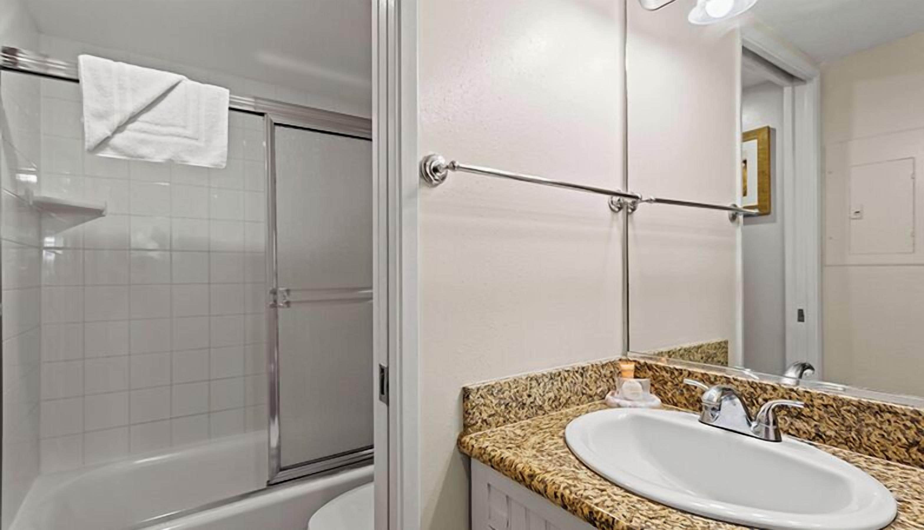 A bathroom with a shower, a sink, and a mirror.
