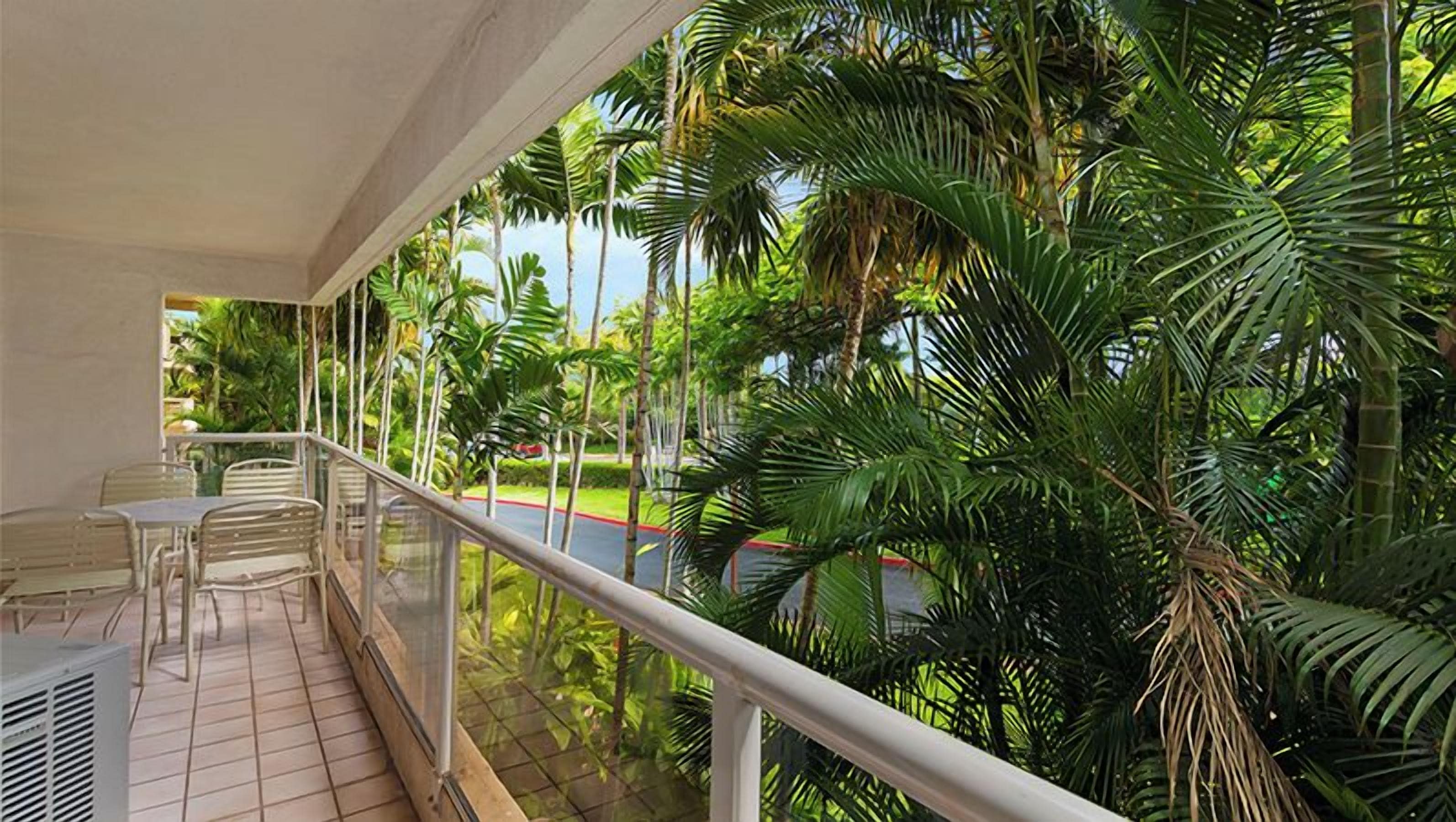 Een balkon met uitzicht op palmbomen en een betegelde vloer.