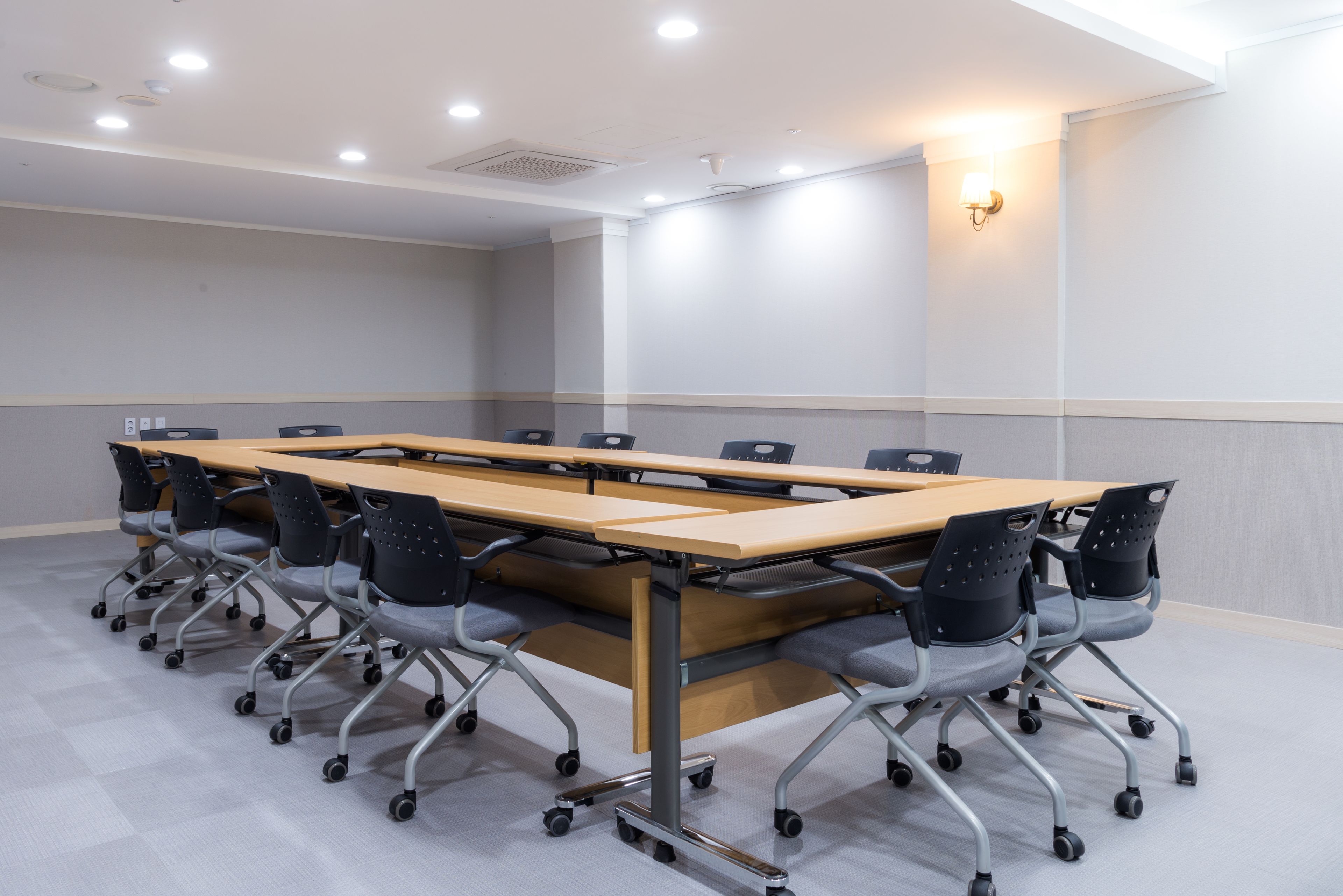 A conference room with a long table, six chairs, and a light fixture on the wall.