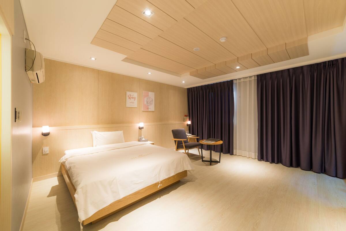 A modern hotel room with a large bed, a desk, and a chair.