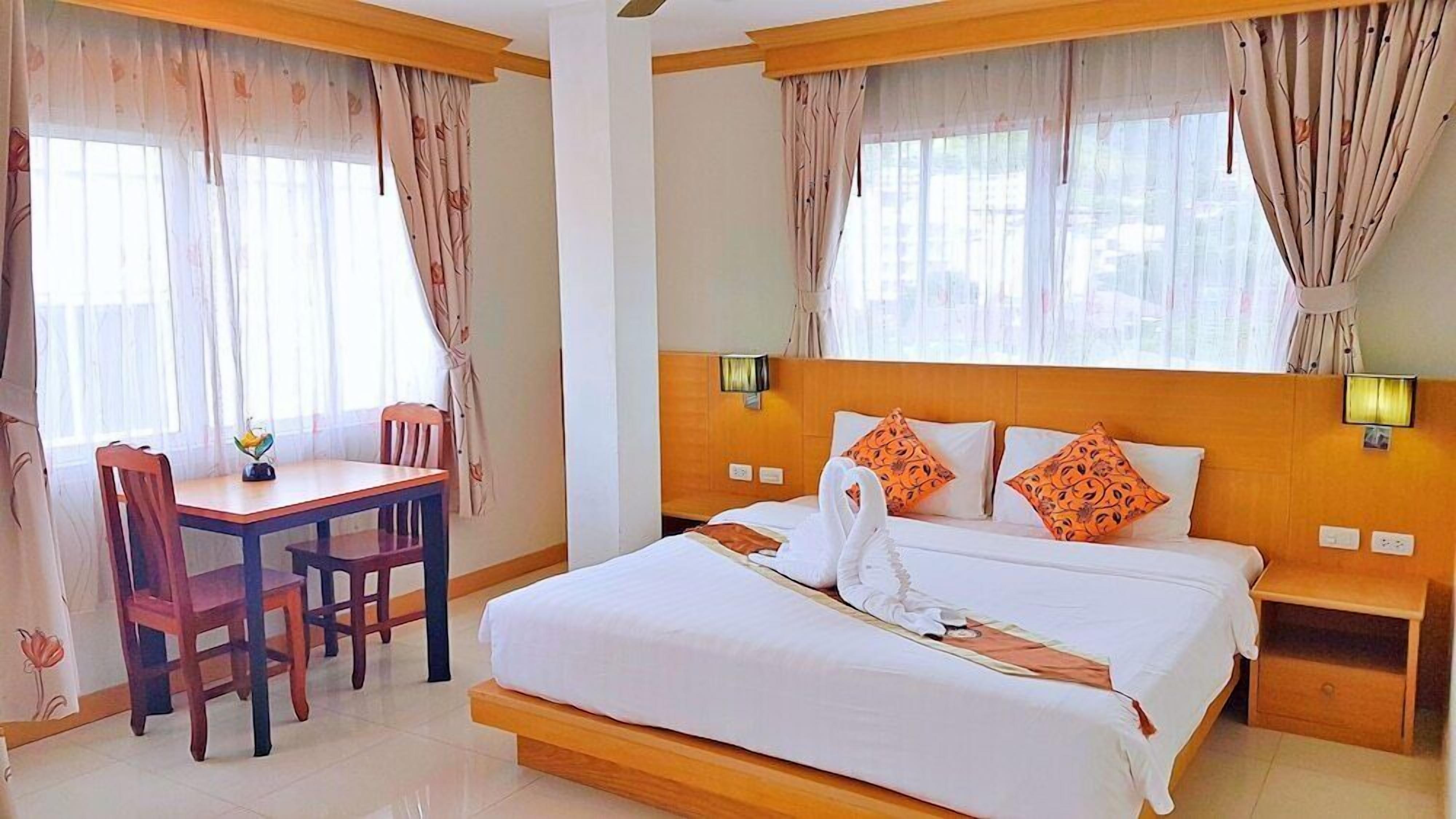 A hotel room with a bed, a desk, and chairs.