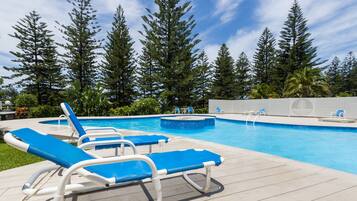 Relax by the pool surrounded by lush evergreen trees and lounge chairs.