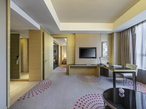 Una habitación de hotel con cama, escritorio, televisión y silla.