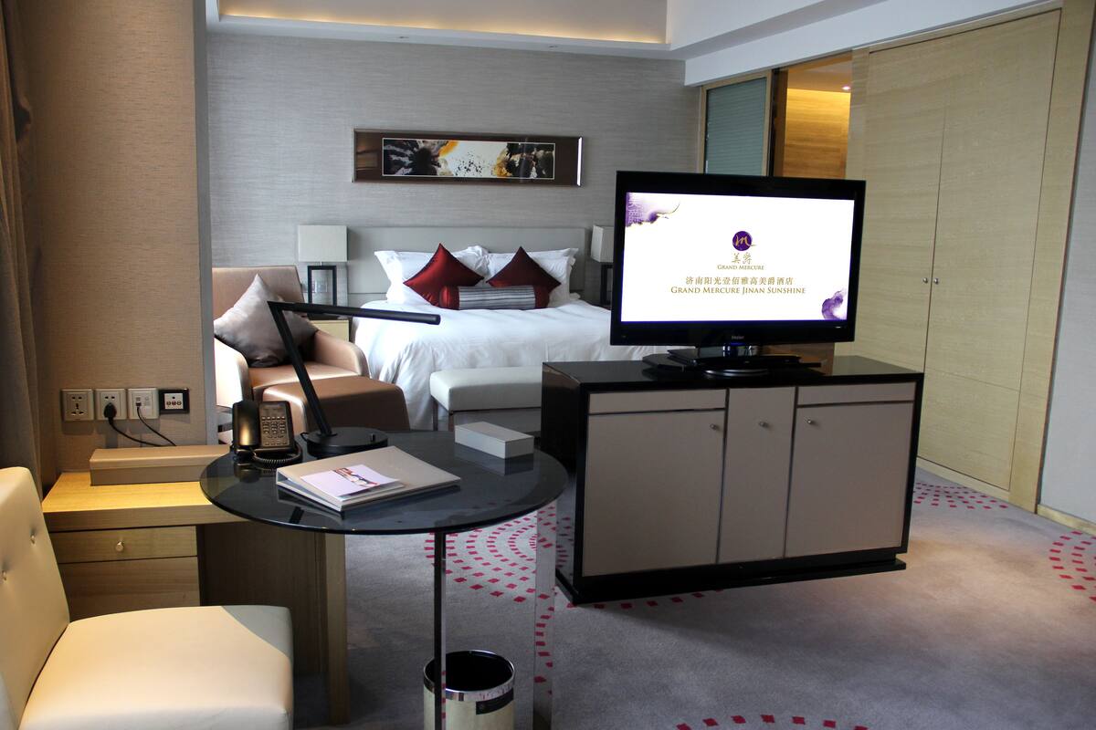 Ein Hotelzimmer mit Bett, Fernseher, Schreibtisch mit Stuhl und Kleiderschrank.