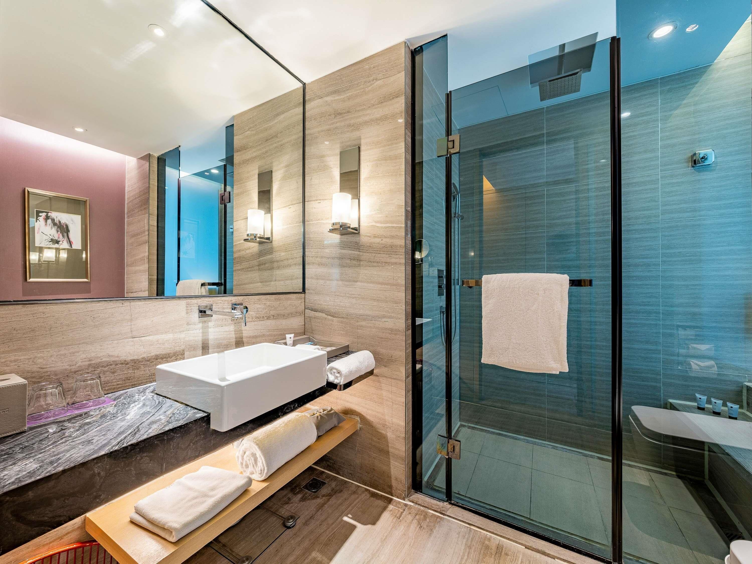 Ein modernes Badezimmer mit einer Duschkabine aus Glas, einer weißen Badewanne und einem Waschtisch mit Spiegel.