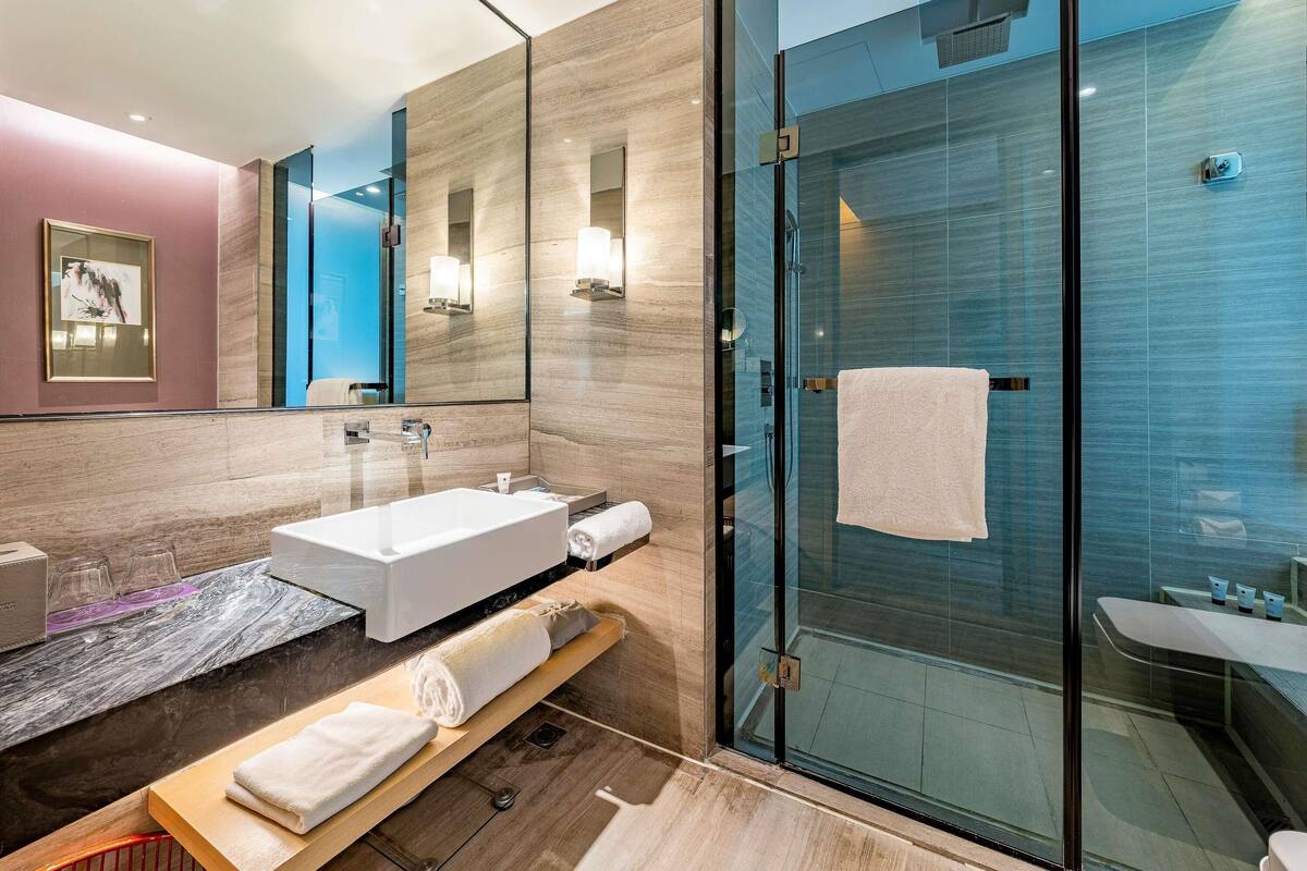 A modern bathroom with a glass shower enclosure, a white bathtub, and a vanity with a mirror.