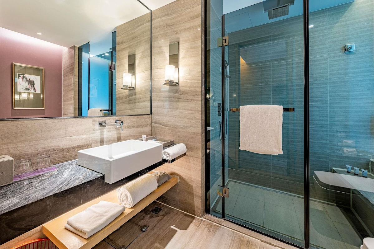 Une salle de bain moderne avec une douche à l’italienne en verre, une baignoire blanche et un meuble-lavabo avec un miroir.