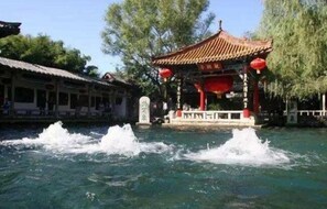 A traditional pavilion over a water feature with a clear sky and trees in the background. - Grand Mercure Jinan Sunshine (Jinan)
