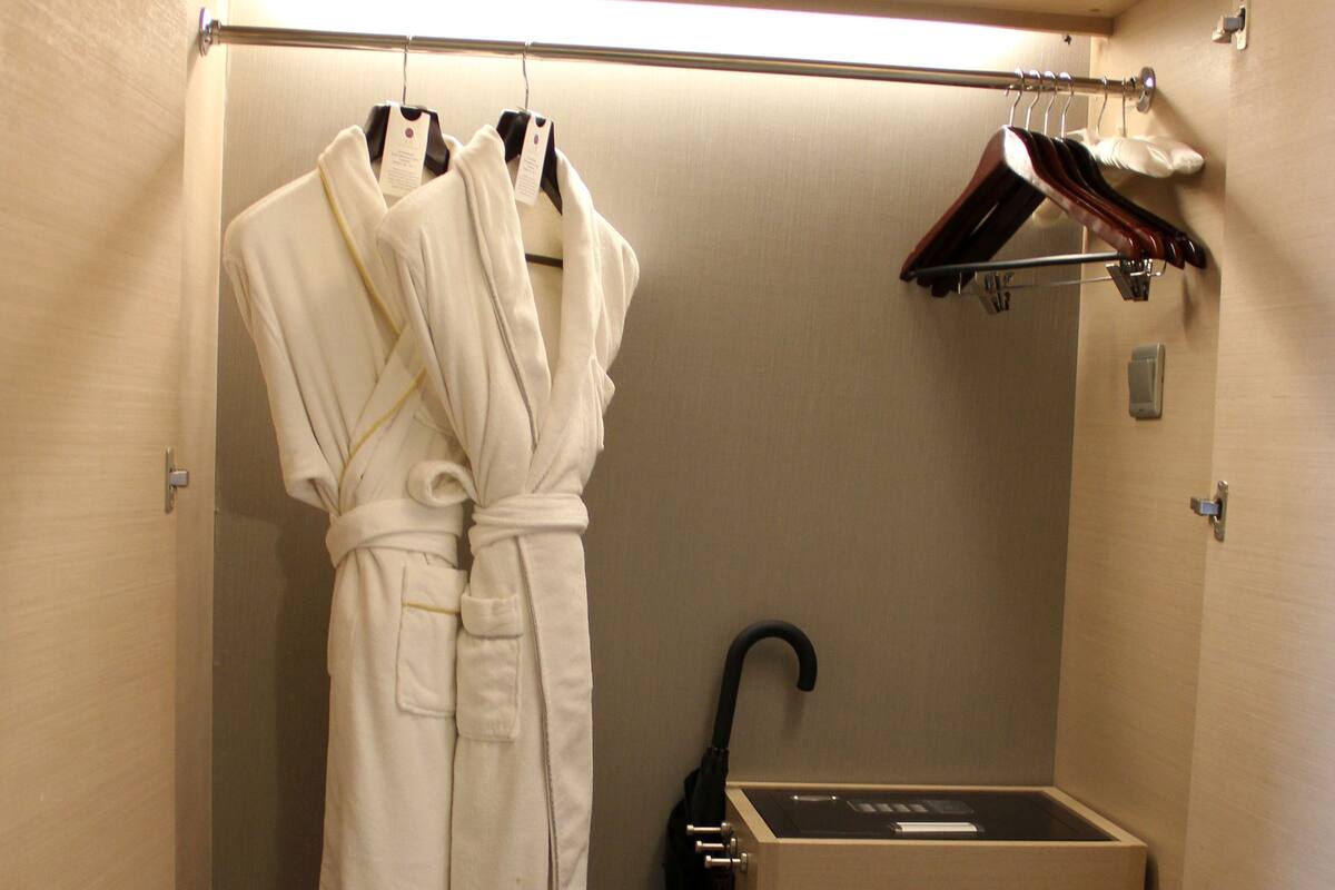 Ein begehbarer Kleiderschrank mit Bademantel, Kleiderstange, Schuhregal und Schuhaufbewahrungsbox.