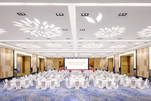 A conference room with round tables, white chairs, and a large screen displaying "GRAND MERCURY". - Grand Mercure Jinan Sunshine (Jinan)