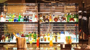 Eine Bar mit Regalen voller verschiedener Spirituosenflaschen, einem Eimer und einigen Cocktails.