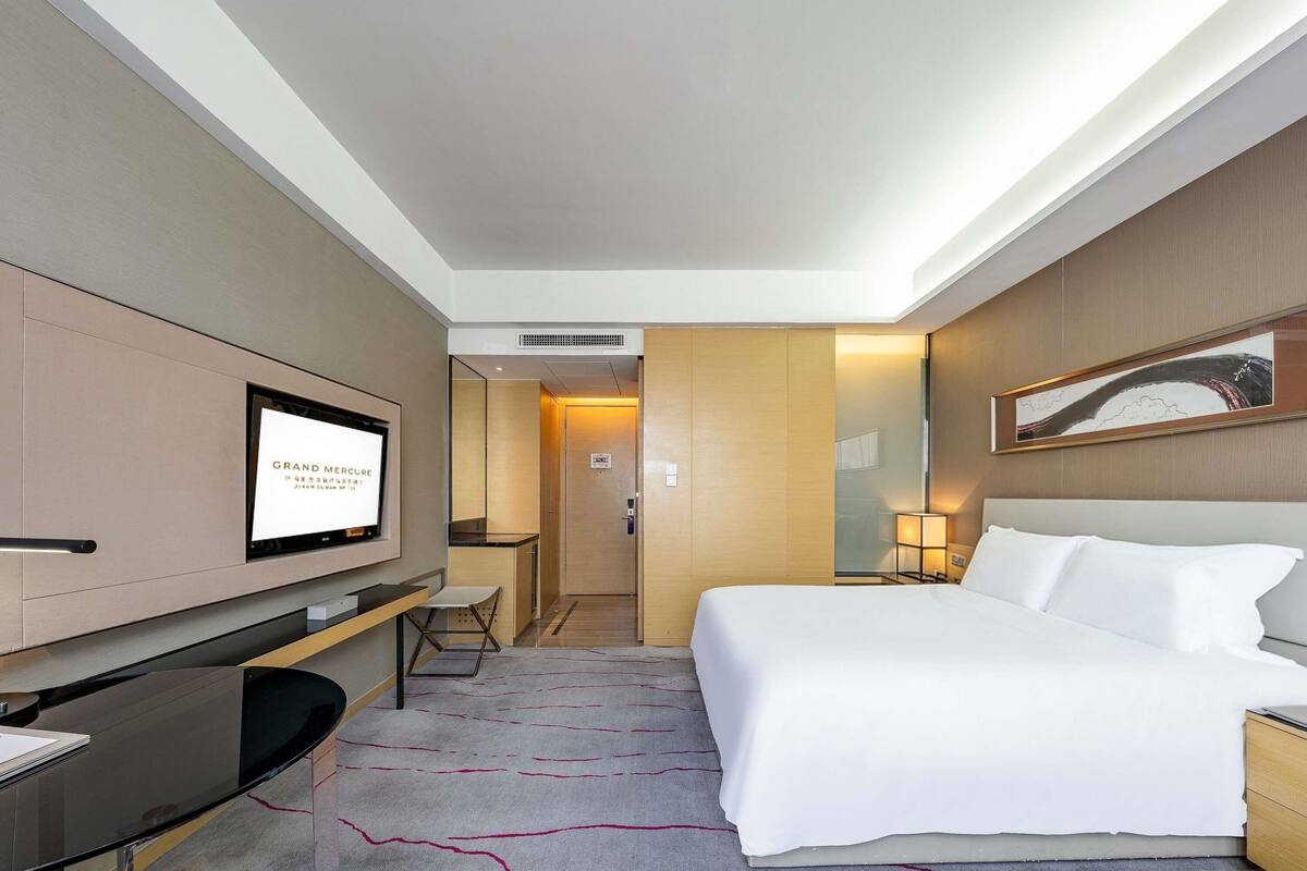 Ein Hotelzimmer mit Bett, Schreibtisch, Fernseher und einer Tür zum Badezimmer.