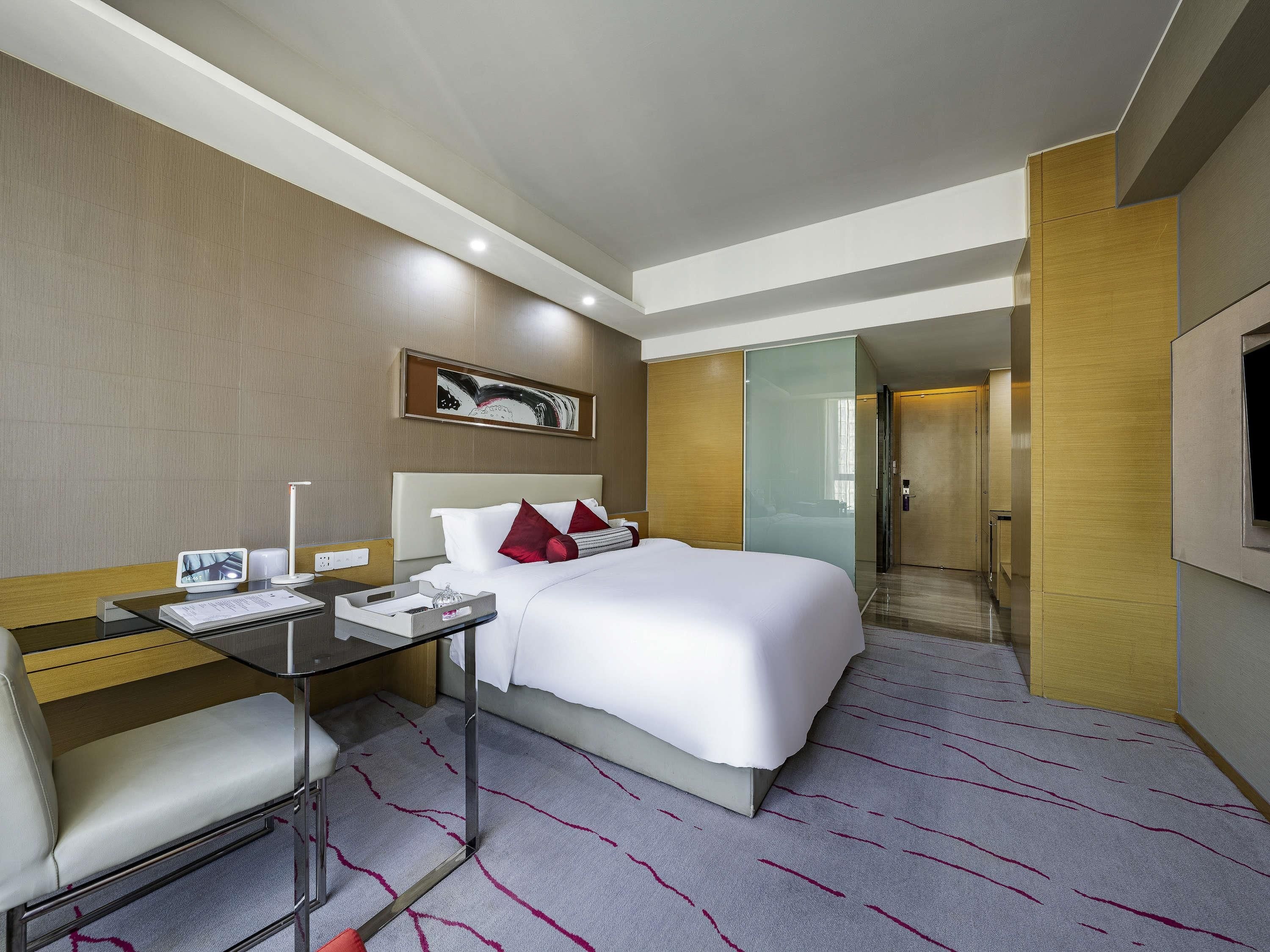 A hotel room with a bed, desk, chair, and a television.