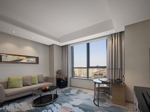 Ein modernes Wohnzimmer mit einer Couch, einem Couchtisch und Blick auf die Stadt durch große Fenster.