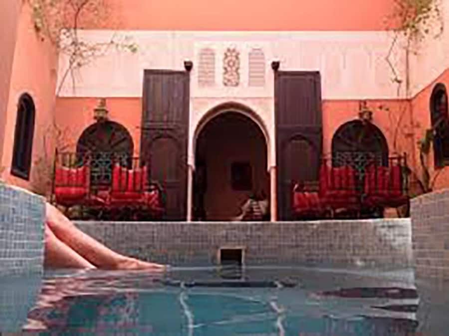 Una piscina al aire libre, sombrillas, sillones reclinables de piscina