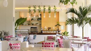 A modern dining area with round tables and chairs, a kitchen in the background, and hanging plants. - The Oriental Legazpi (Legazpi)
