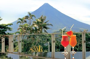 Dos bebidas sobre una superficie reflectante, con una montaña al fondo.
