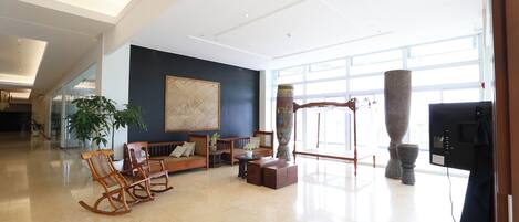 A spacious lobby with a seating area, large windows, and a modern ceiling design.