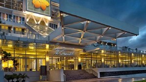 A modern hotel with a prominent logo, a covered entrance, and a staircase leading to the lobby. - The Oriental Legazpi (Legazpi)