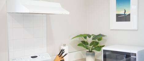 A kitchen with a white stove, a microwave, a knife block, and a potted plant.