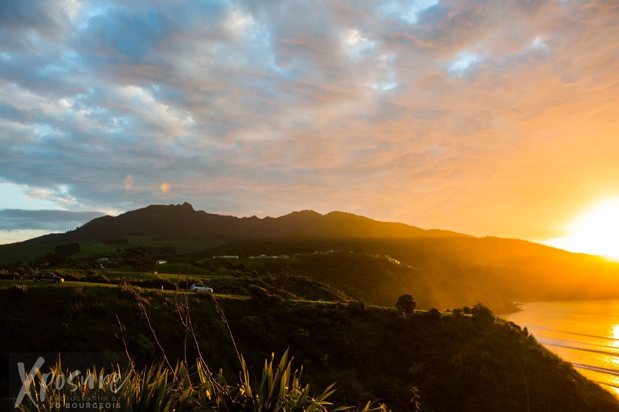 Un paysage côtier avec des collines douces et un coucher de soleil.