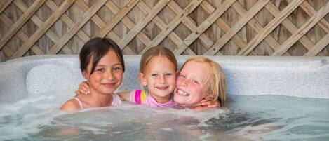 Tres niños en un jacuzzi con un muro de celosía de madera al fondo.