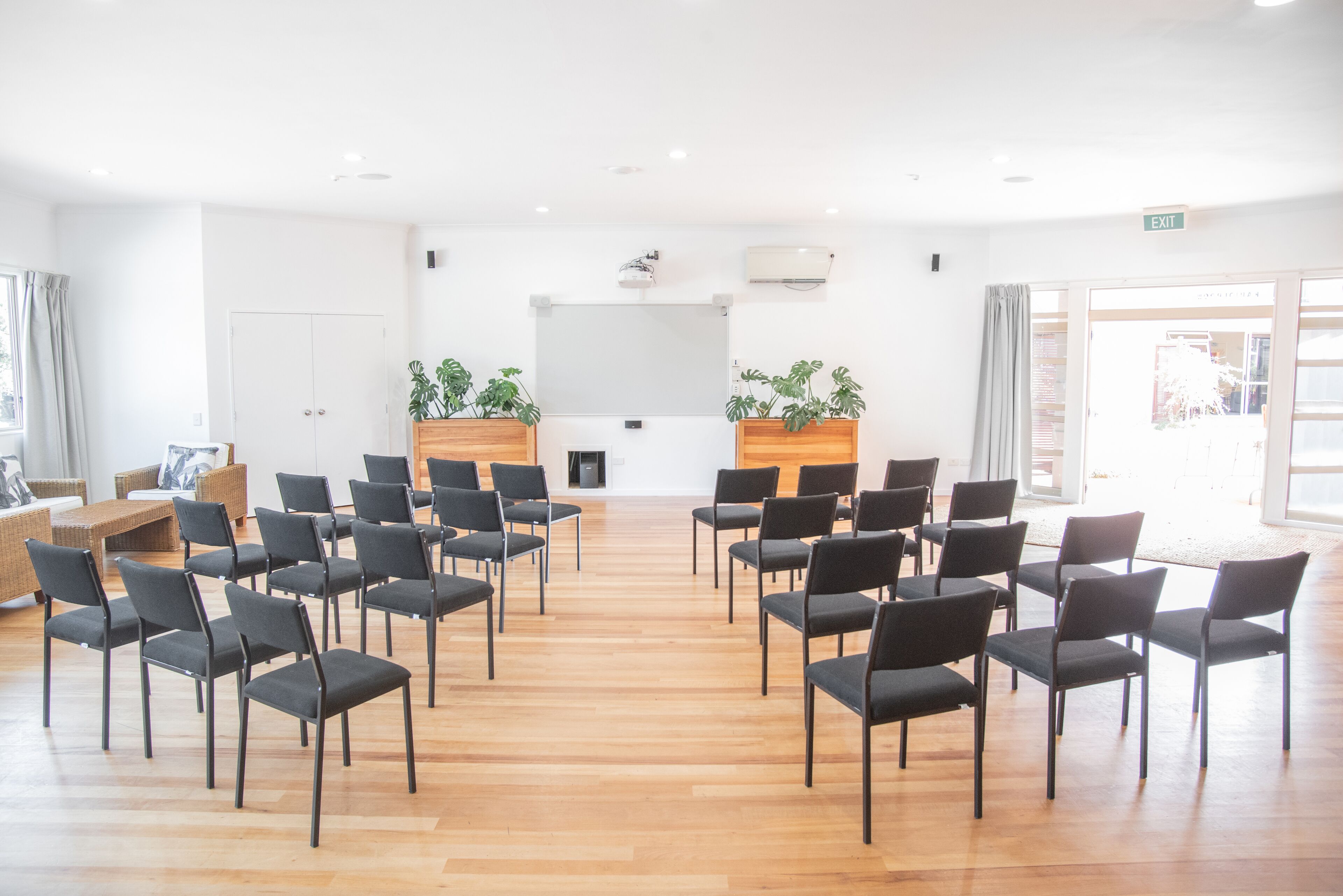 A conference room with rows of chairs, a wooden podium, and potted plants.