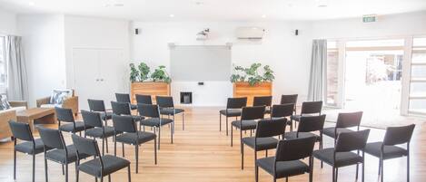 A conference room with rows of chairs, a wooden podium, and potted plants.
