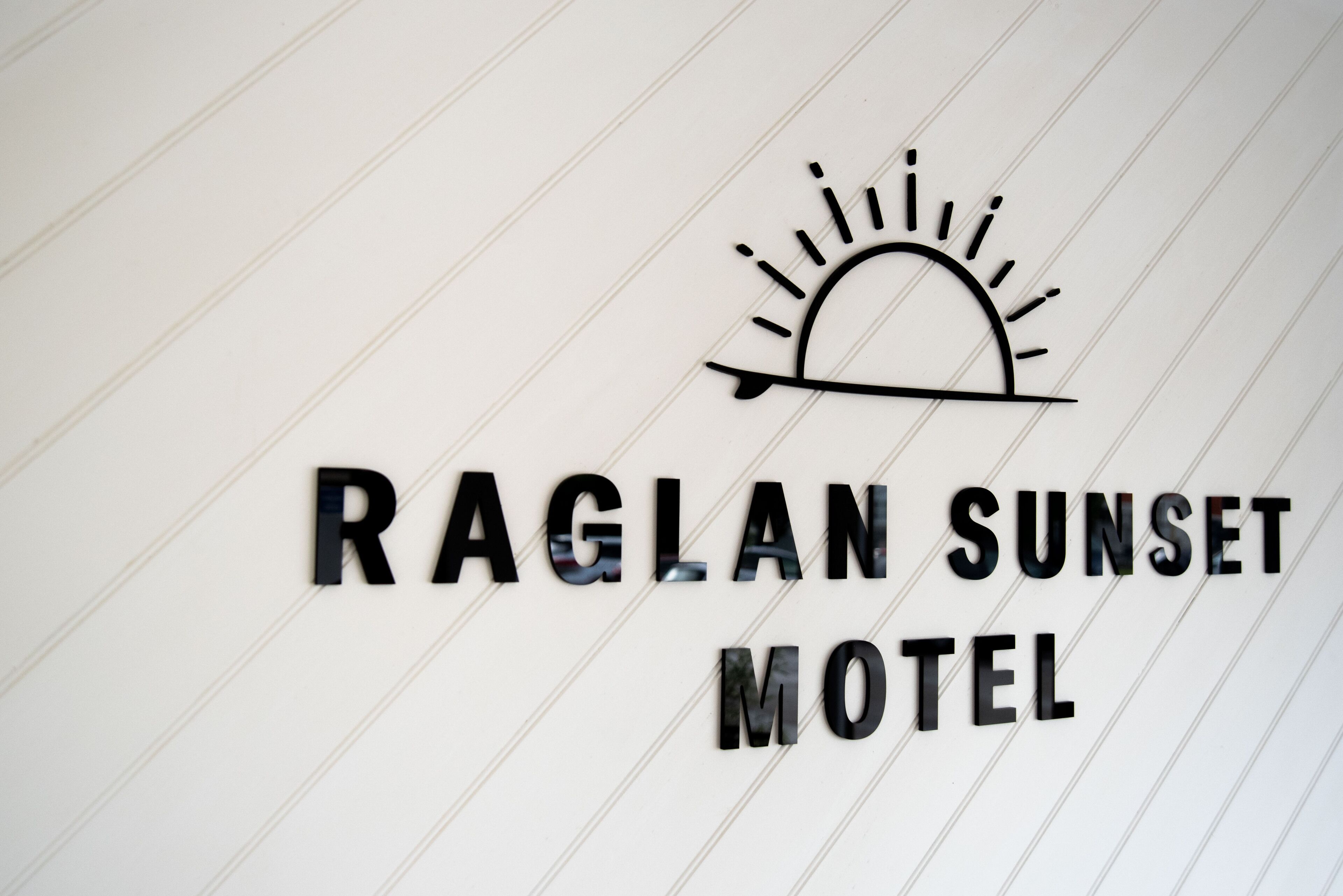 A sign for the Raglan Sunset Motel with a sun graphic.