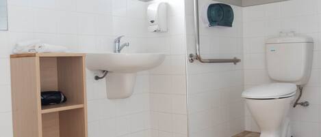 Baño con lavamanos, inodoro y estante de madera.