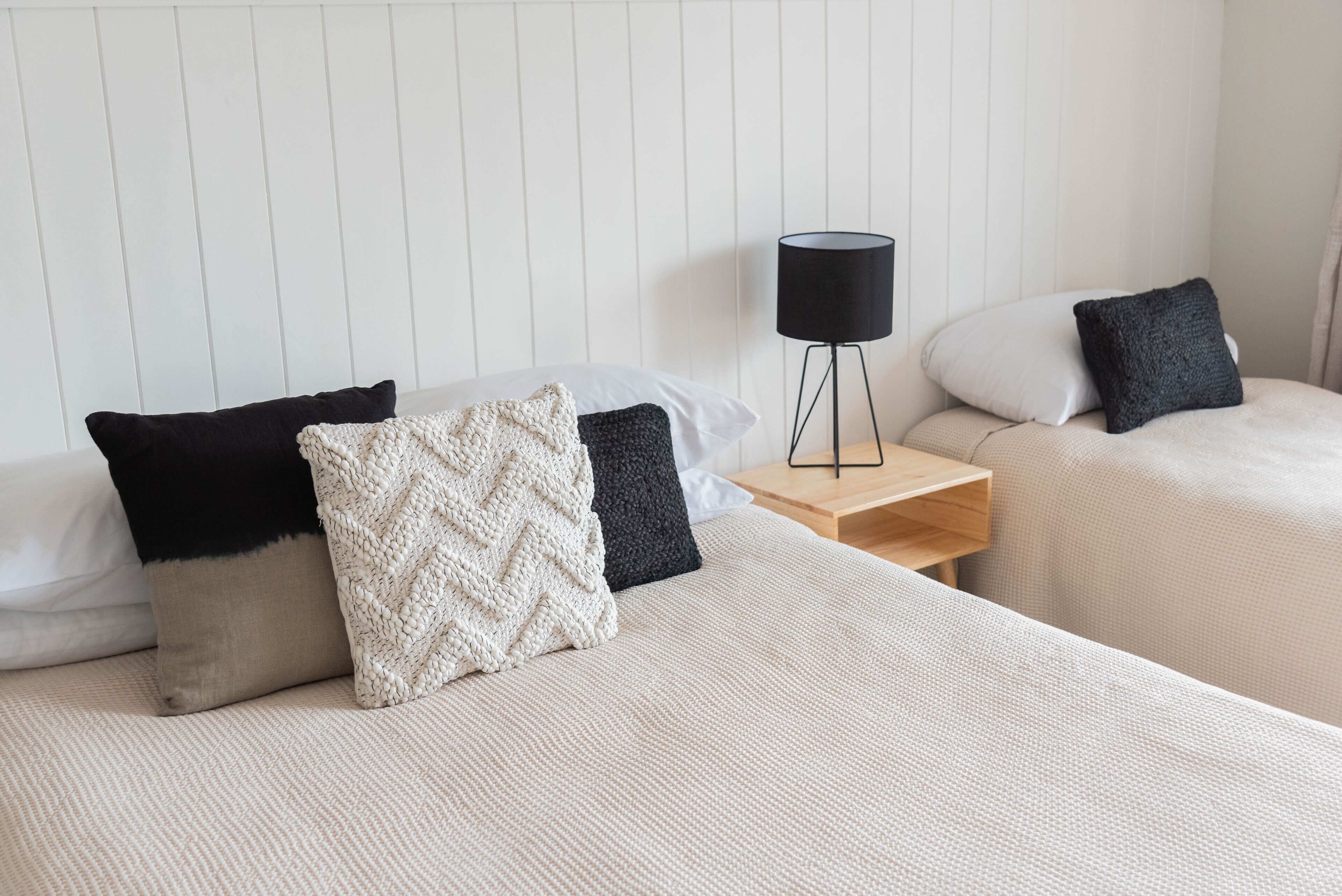A neatly arranged hotel room with two beds, each with a different pillow arrangement.