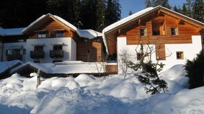A wooden chalet with a sloped roof, surrounded by snow. - Hotel Bad Schoergau (Sarentino)