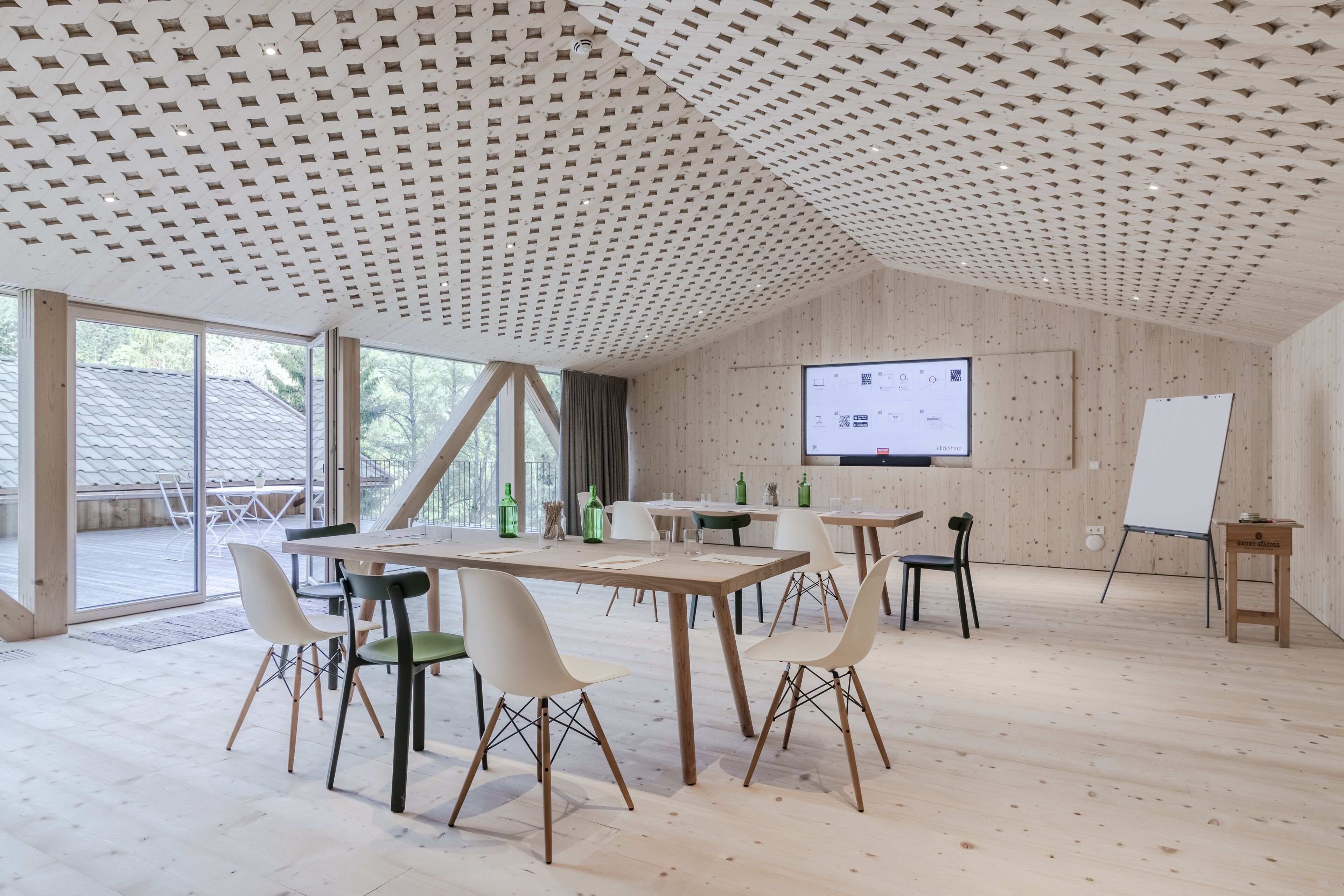Una camera spaziosa con soffitto in legno, ampie finestre e uno schermo proiettore a parete.