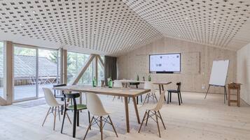 Una camera spaziosa con soffitto in legno, ampie finestre e uno schermo proiettore a parete.
