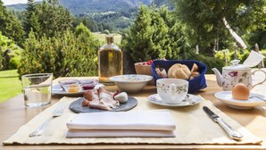 A picnic setup with food and drinks on a table, surrounded by a scenic mountain view. - Hotel Bad Schoergau (Sarentino)