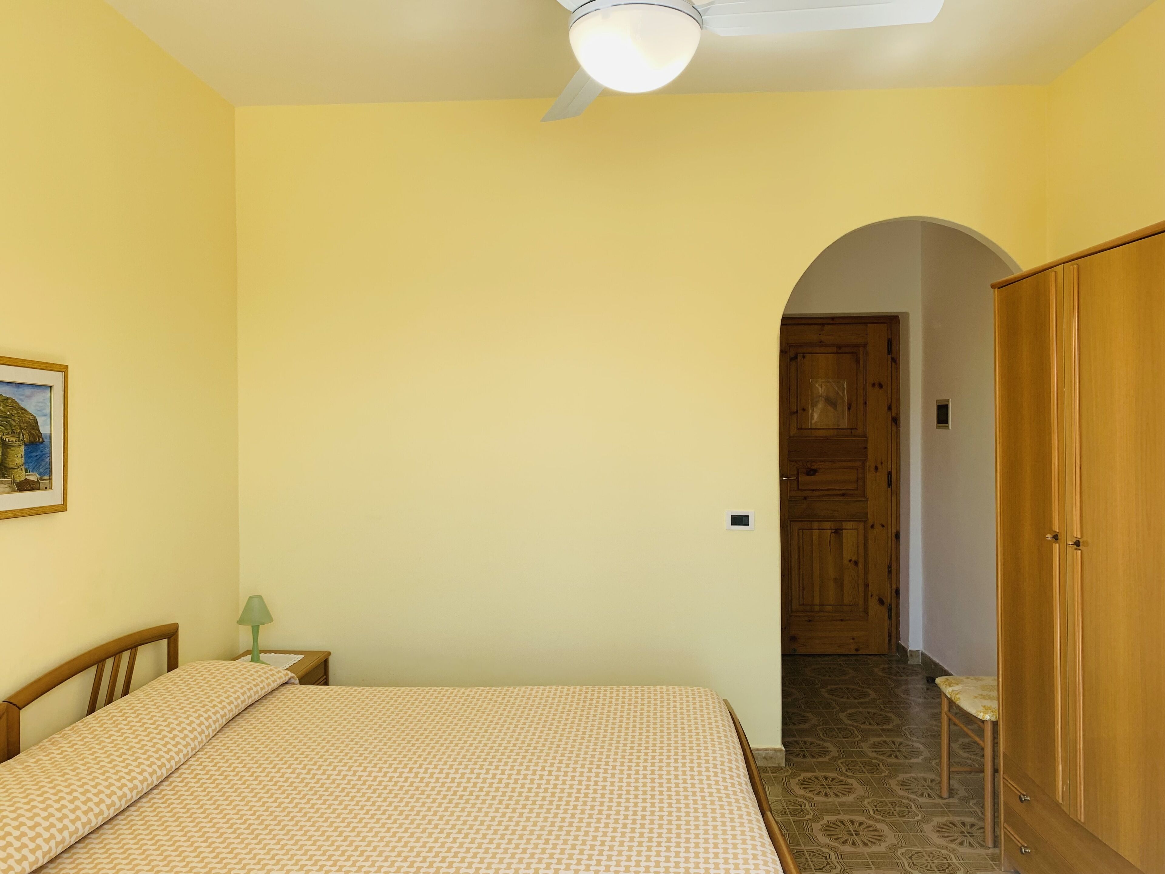 Une chambre à coucher avec un lit, une table de chevet, une lampe et une armoire.