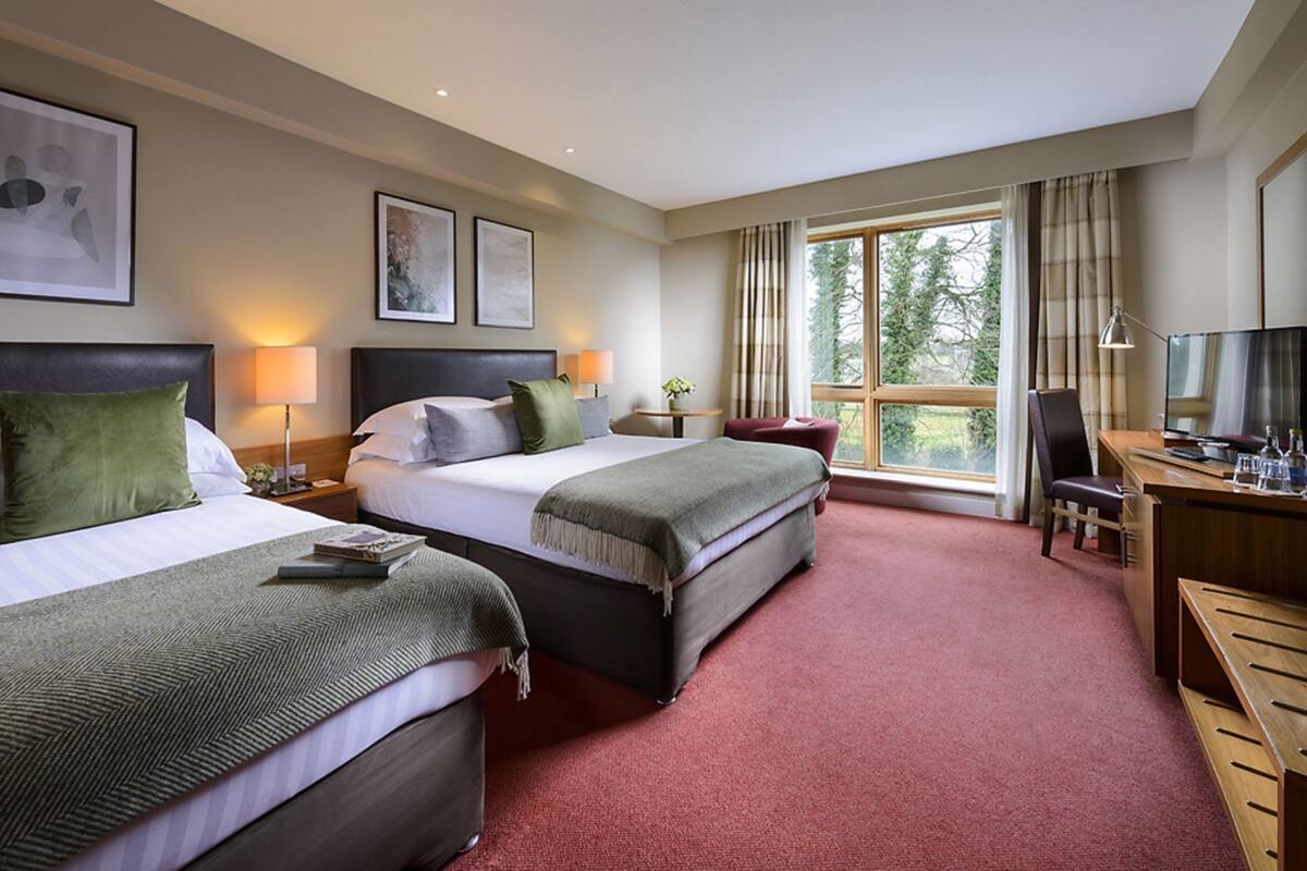 Ein Hotelzimmer mit zwei Betten, einem Schreibtisch, einem Stuhl und einem Fernseher.