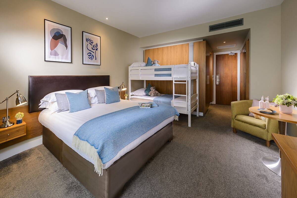 Ein Hotelzimmer mit einem großen Bett, Stockbetten, einem Schreibtisch und einem Stuhl.