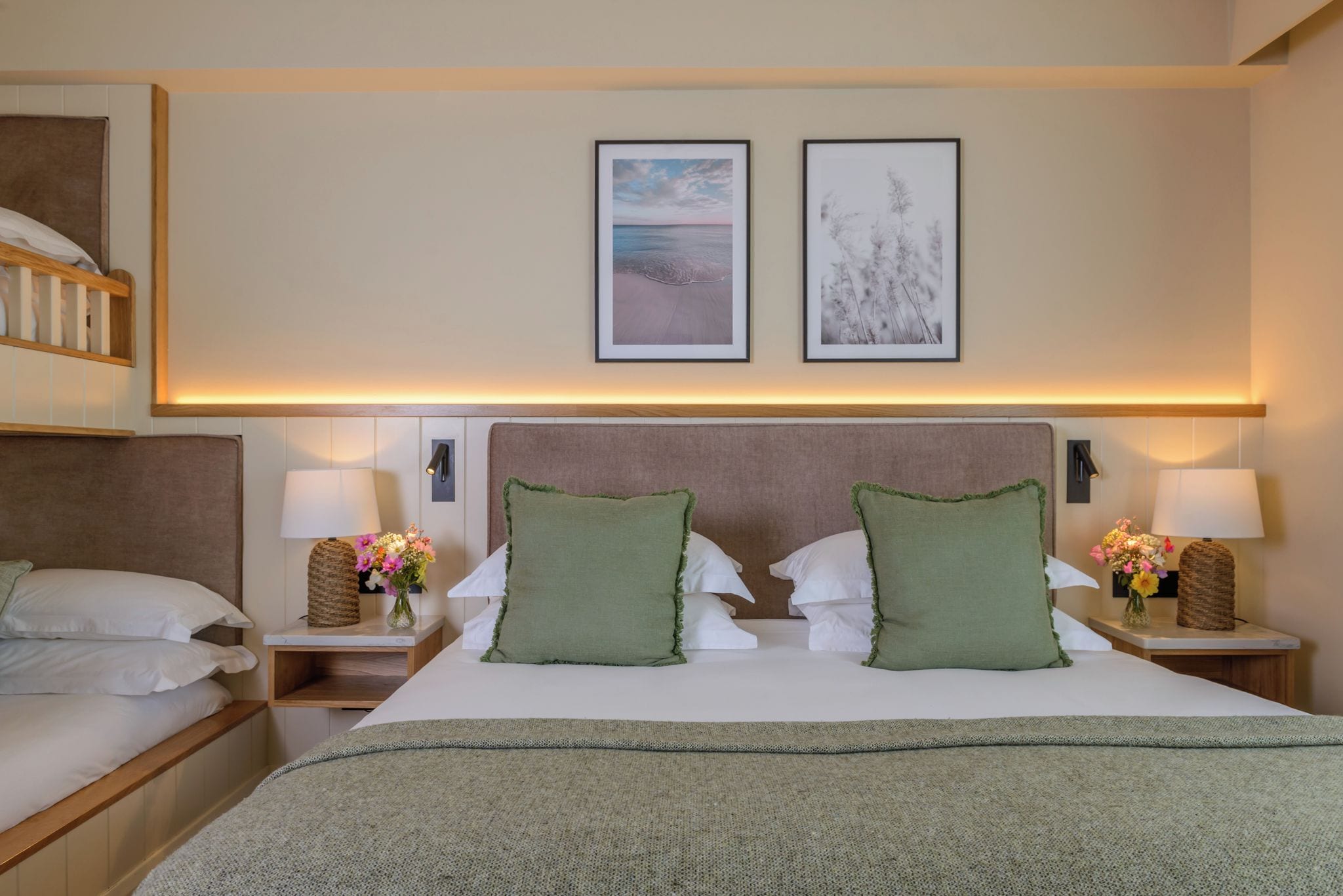 Ein Hotelzimmer mit einem großen Bett, zwei Nachttischen, einer Kopfteil und zwei gerahmten Bildern an der Wand.