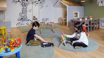 A room with a play area, a dining table, and a wall mural.