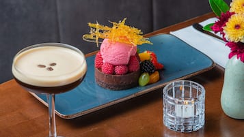 Un postre sobre un plato azul, con un vaso de una bebida cremosa a su lado.